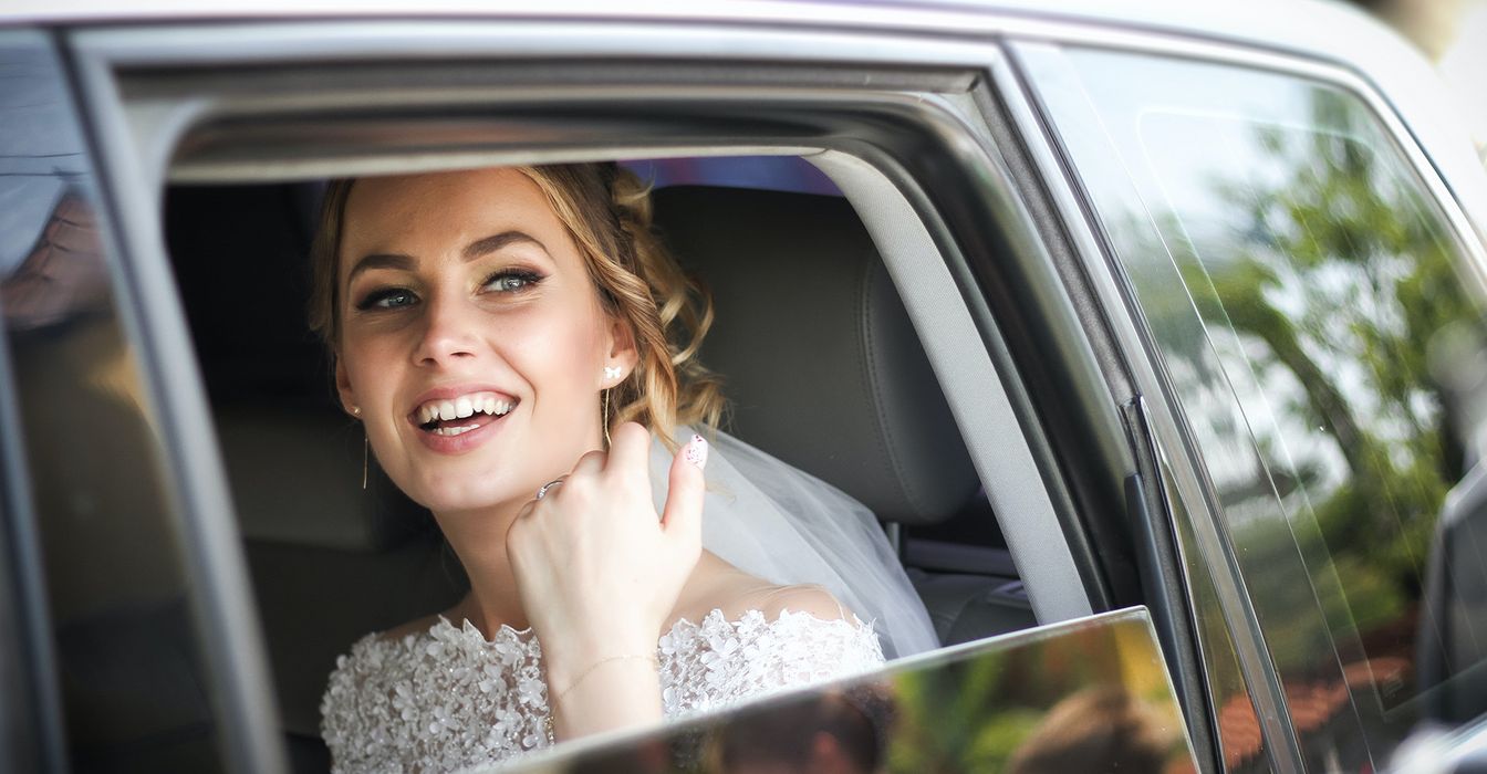 A bride smiling while looking out of a car window