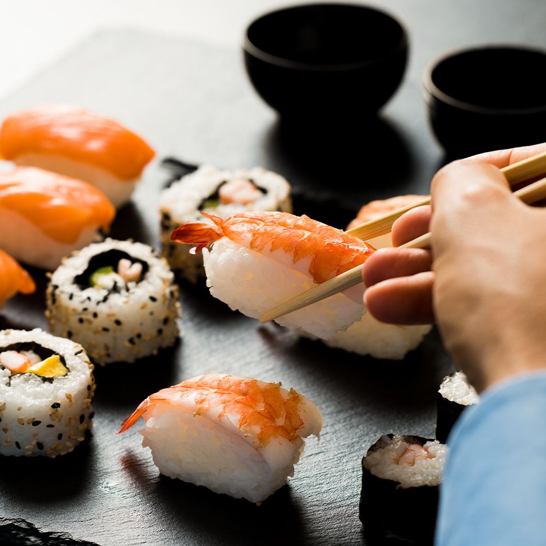 Person using chopsticks to pick up sushi