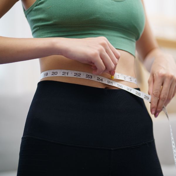 fit woman measuring waist