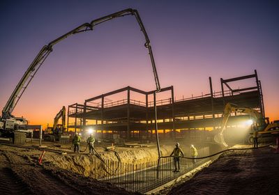 Construction site at dusk with heavy machinery and workers