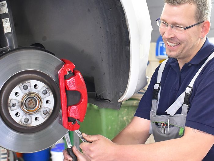 Mechanic testing brake system on vehicle.