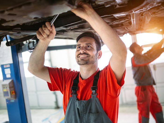 Car mechanic changing motor oil in automotive engine and maintenance repair service station.