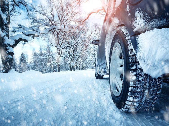 Car tires on winter road that is packed with snow.