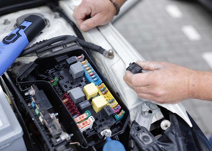 image of Car mechanic working on a car's electronics.