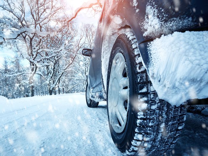 Vehicle with winter tires driving on snowy road.