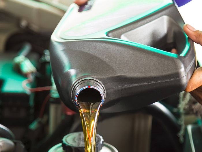 Mechanic pouring new oil into a vehicle.