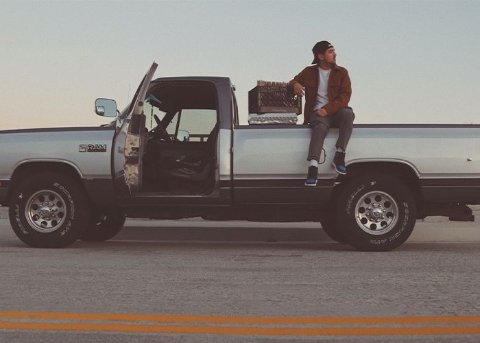 image of man sitting on back of his Ram pickup truck. 