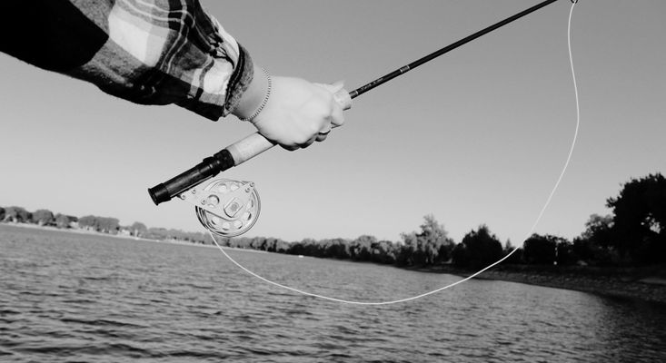 black and white image of fishing rod held over water