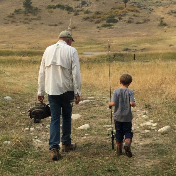 older fisherman walking with child