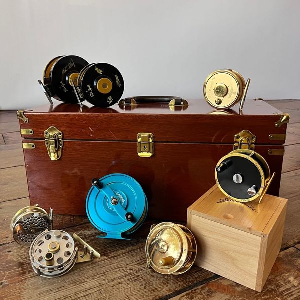 vintage fishing reels resting on and next to wooden box vintage fishing reels resting on and next to wooden box