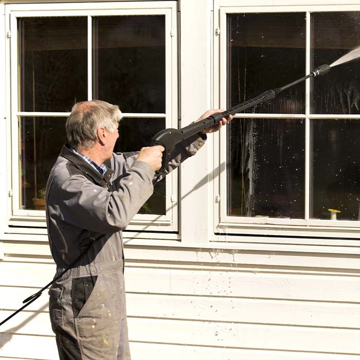 man power washing a set of windows