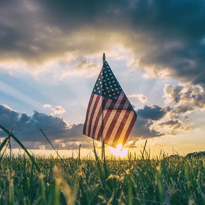 American flag in a field at sunset