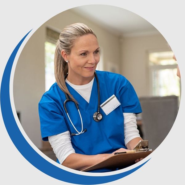 Nurse in blue scrubs and a stethoscope smiling warmly while holding a clipboard, representing compassionate medical care.