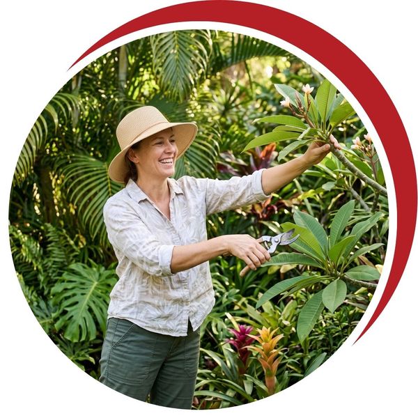 Woman comfortably using pruning shears to trim tropical garden plants in Fort Myers.