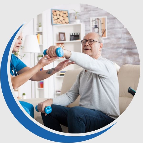 Elderly man performing arm physical therapy with small weights, guided by a nurse or physical therapist, inside a comfortable home setting.