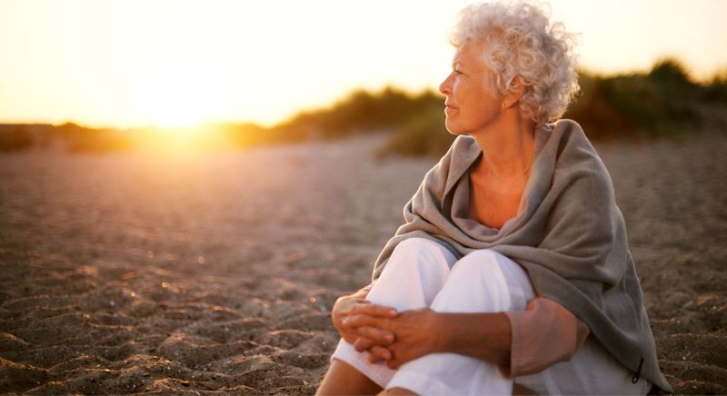 woman sitting on beach looking off into the distance