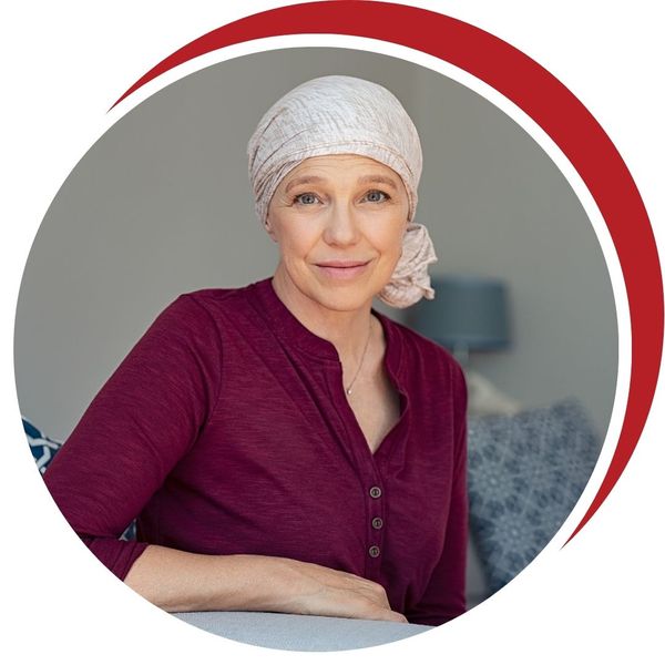 Middle-aged woman with a head covering (turban or scarf), smiling confidently and looking directly at the camera, symbolizing comfort and quality of life during cancer treatment.