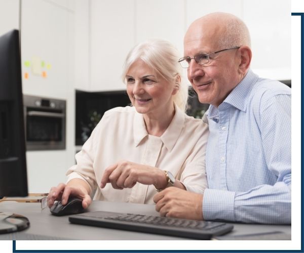 an elderly couple looking at the computer togther