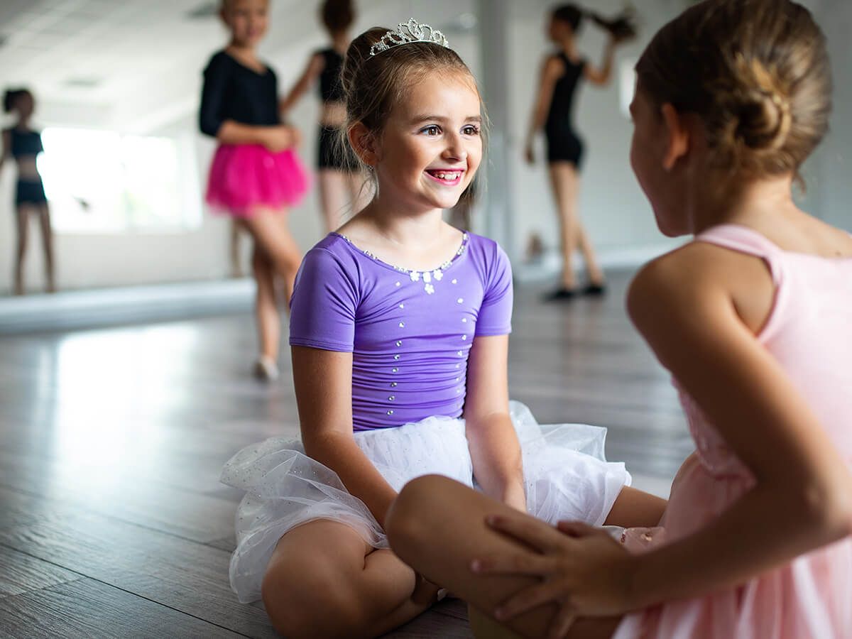Group of fit little ballerinas doing exercises in dance school.