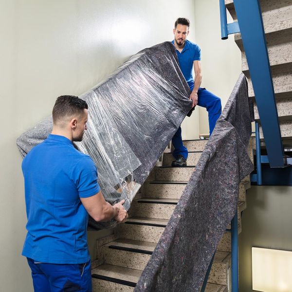 Two movers moving furniture up a staircase