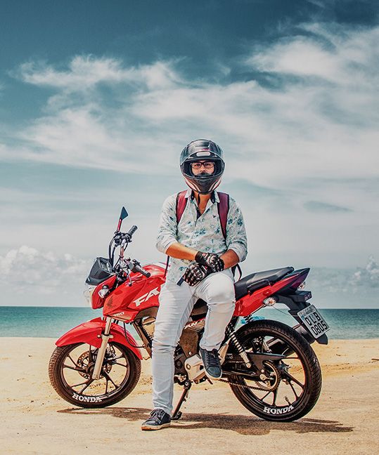 A man leaning on his motorcycle on the beach