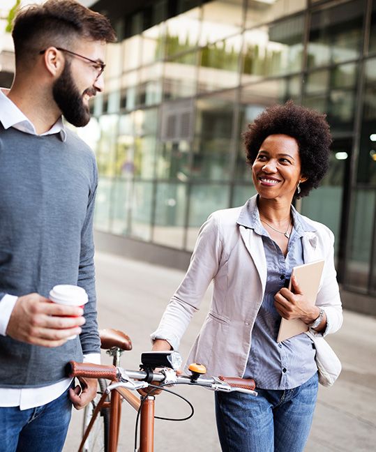 A woman walking her bike while talking to a coworker