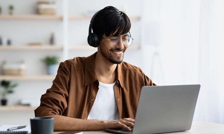 a person listening in headphones in front of a laptop