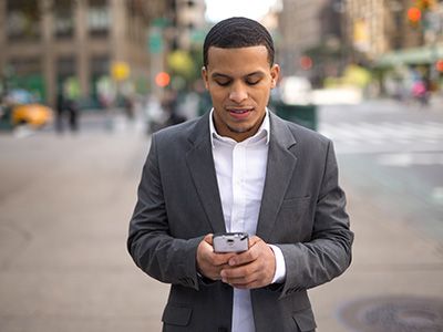 man walking down city street looking at smart phone