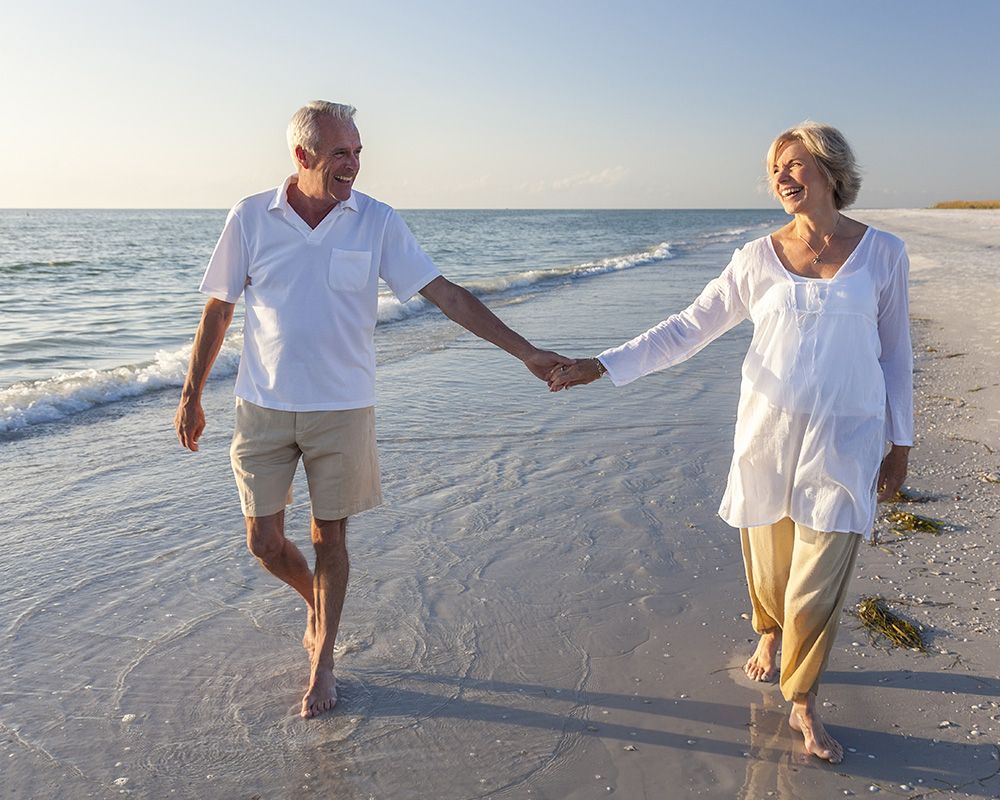 happy older couple walking on beach