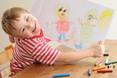 happy disabled boy holding a crayon drawing