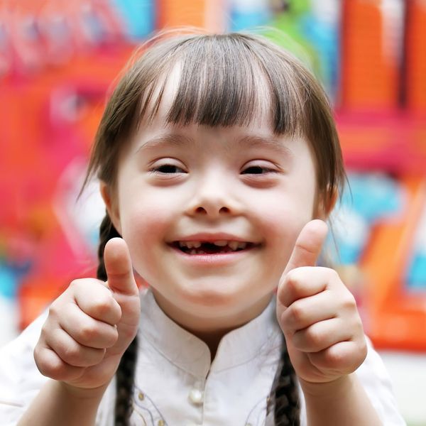 special needs girl smiling and giving thumbs up