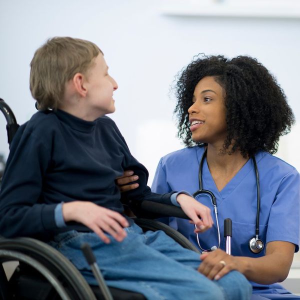 caregiver speaking with boy in wheelchair