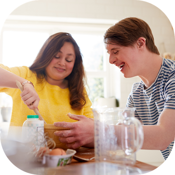 Special needs adult baking with his caregiver