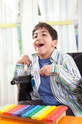 disabled boy happily playing a xylophone