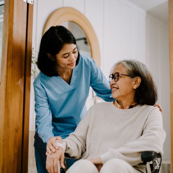 caregiver smiling at older woman in wheelchair