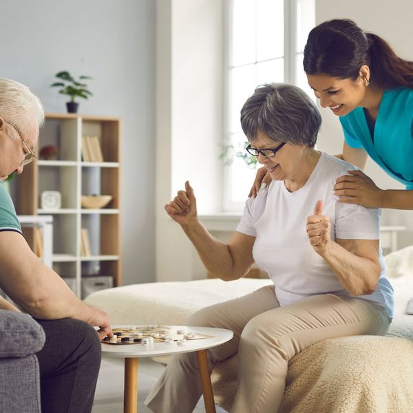 caregiver with seniors playing chess