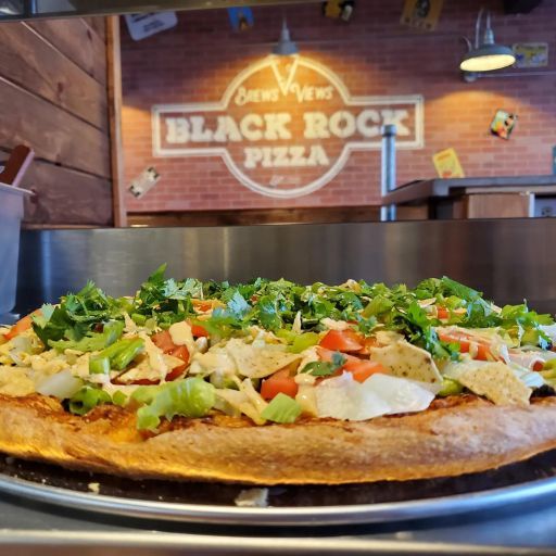 a specialty pizza in front of the Black Rock Pizza logo