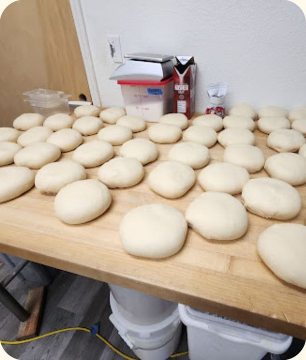 a large table with many fresh pizza dough balls