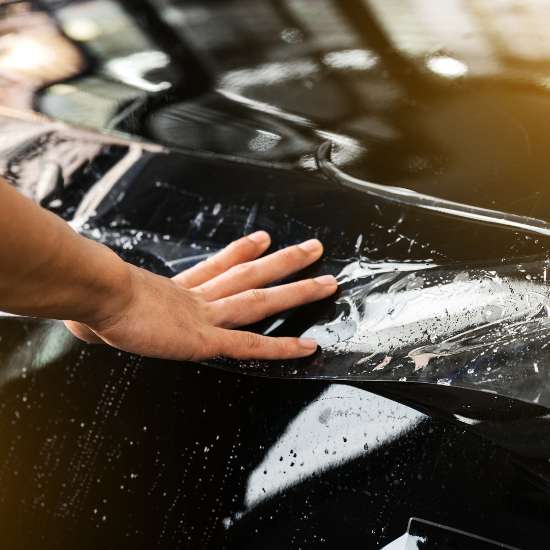 person with their hand on a wet car.