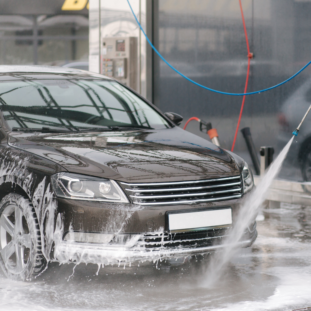 person rinsing a car. 