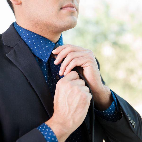 Close up of man tying tie while wearing suit
