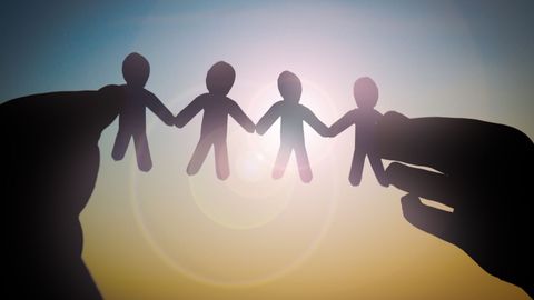 Holding up paper cut out of people holding hands Holding up paper cut out of people holding hands