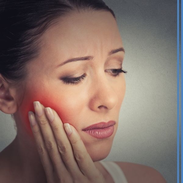 A woman cupping her painful jaw, which is red