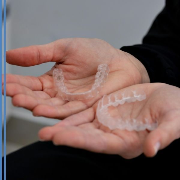 A person holding clear retainers in their hands