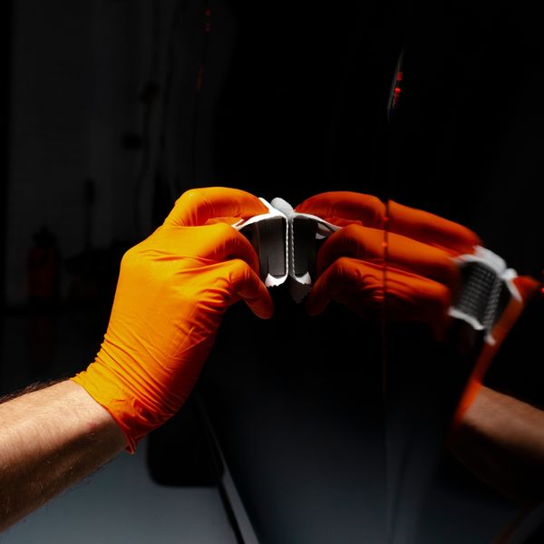 A gloved hand polishing a clean black car
