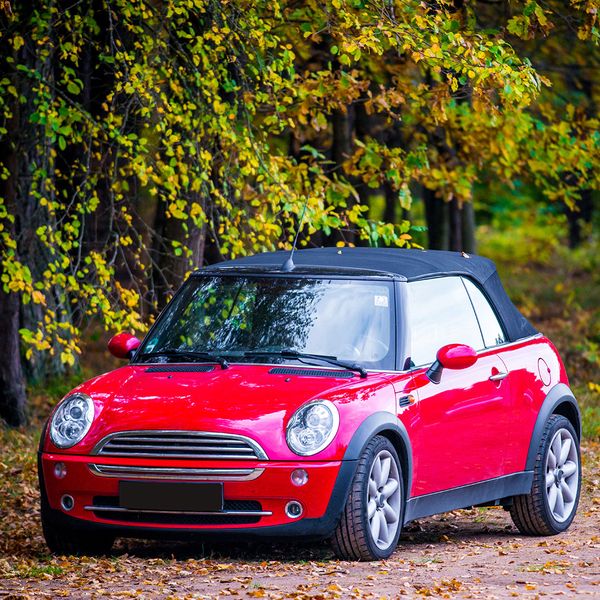 a red mini cooper under a tree with falling leaves