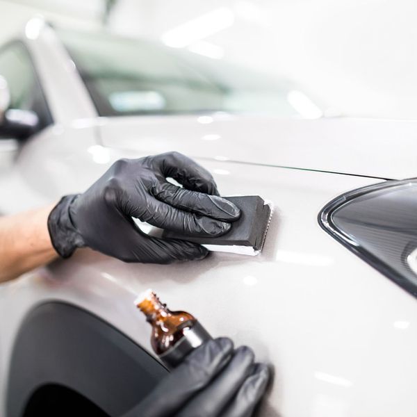 An experienced auto detailer adding wax to a car's exterior