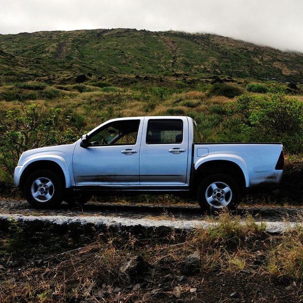 Silver truck driving past a hill in the beginning of spring