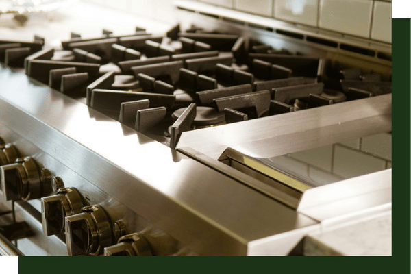 dramatic close-up showing the heavy-duty cast-iron burner grates of a high-end commercial-style stainless steel gas cooktop.