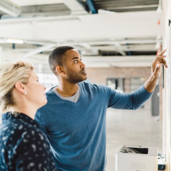 Two office employees going over a whiteboard